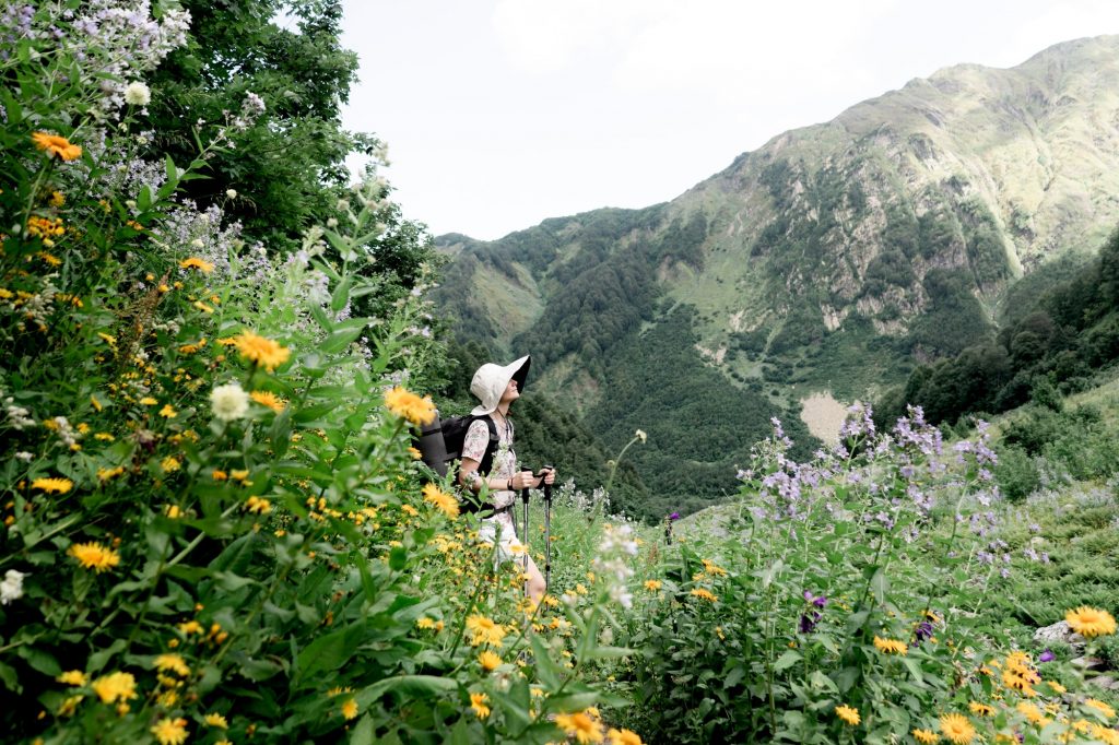 Female person in big hat on a hiking trail in the mountains