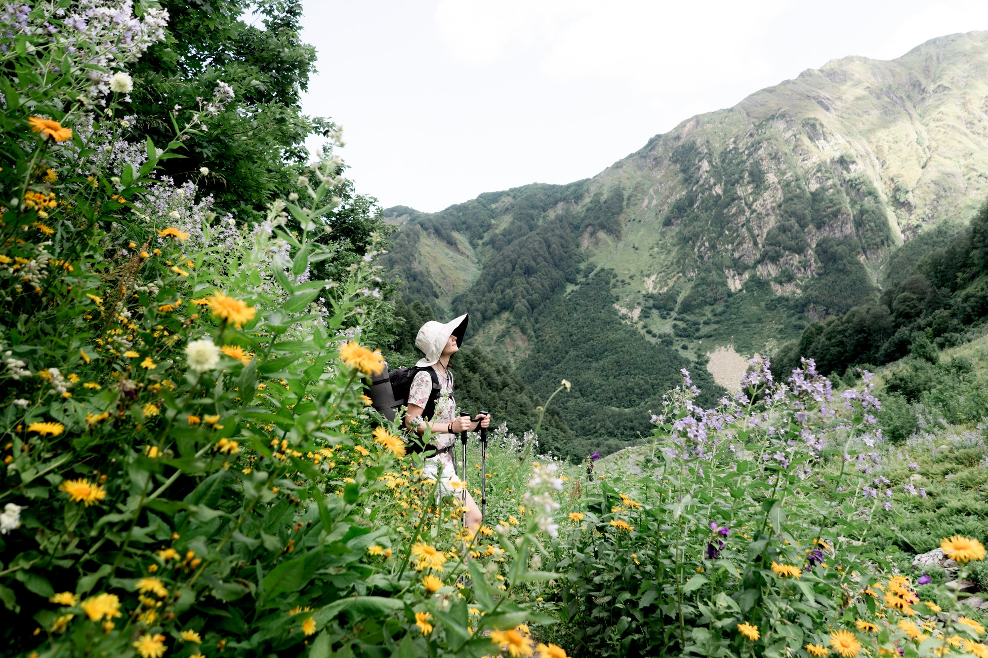 Female person in big hat on a hiking trail in the mountains